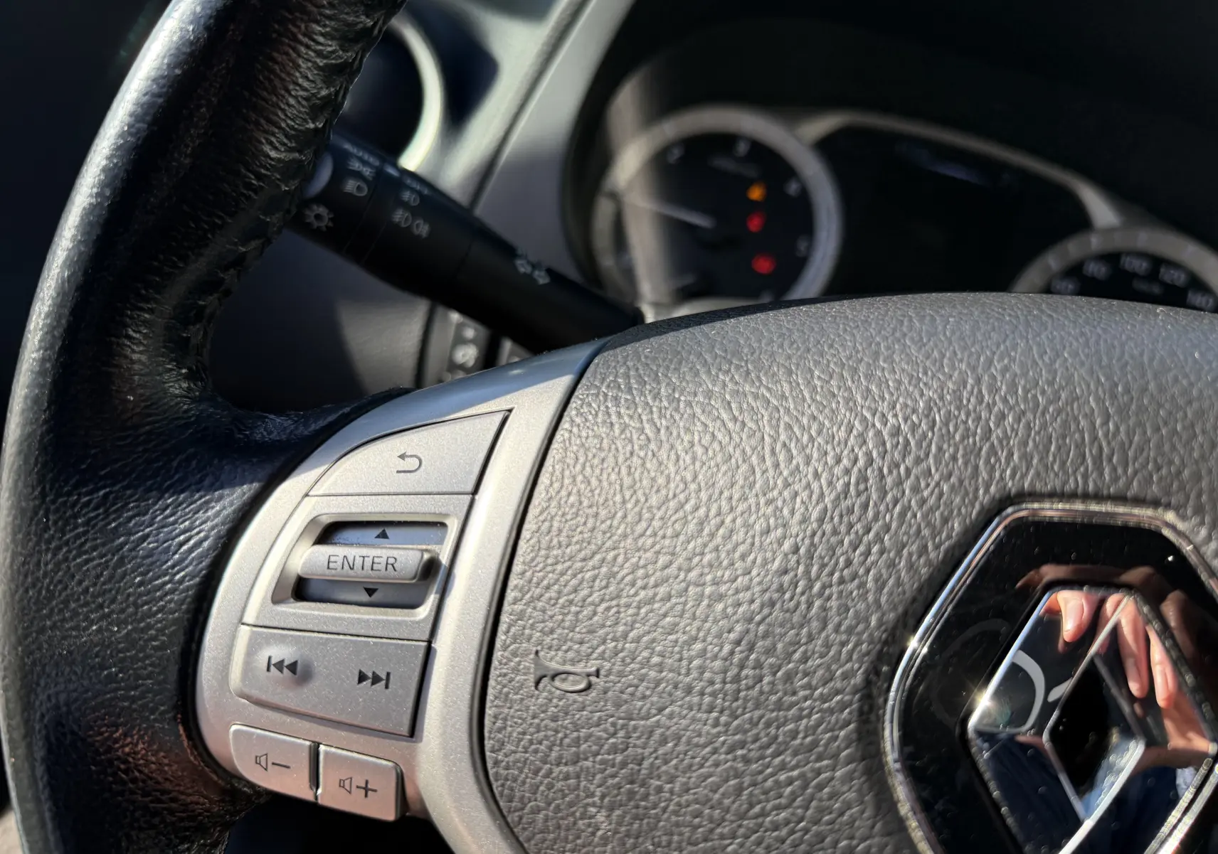 Gros plan sur le volant en cuir noir du Renault Alaskan 2018 avec commandes intégrées et logo chromé Renault.