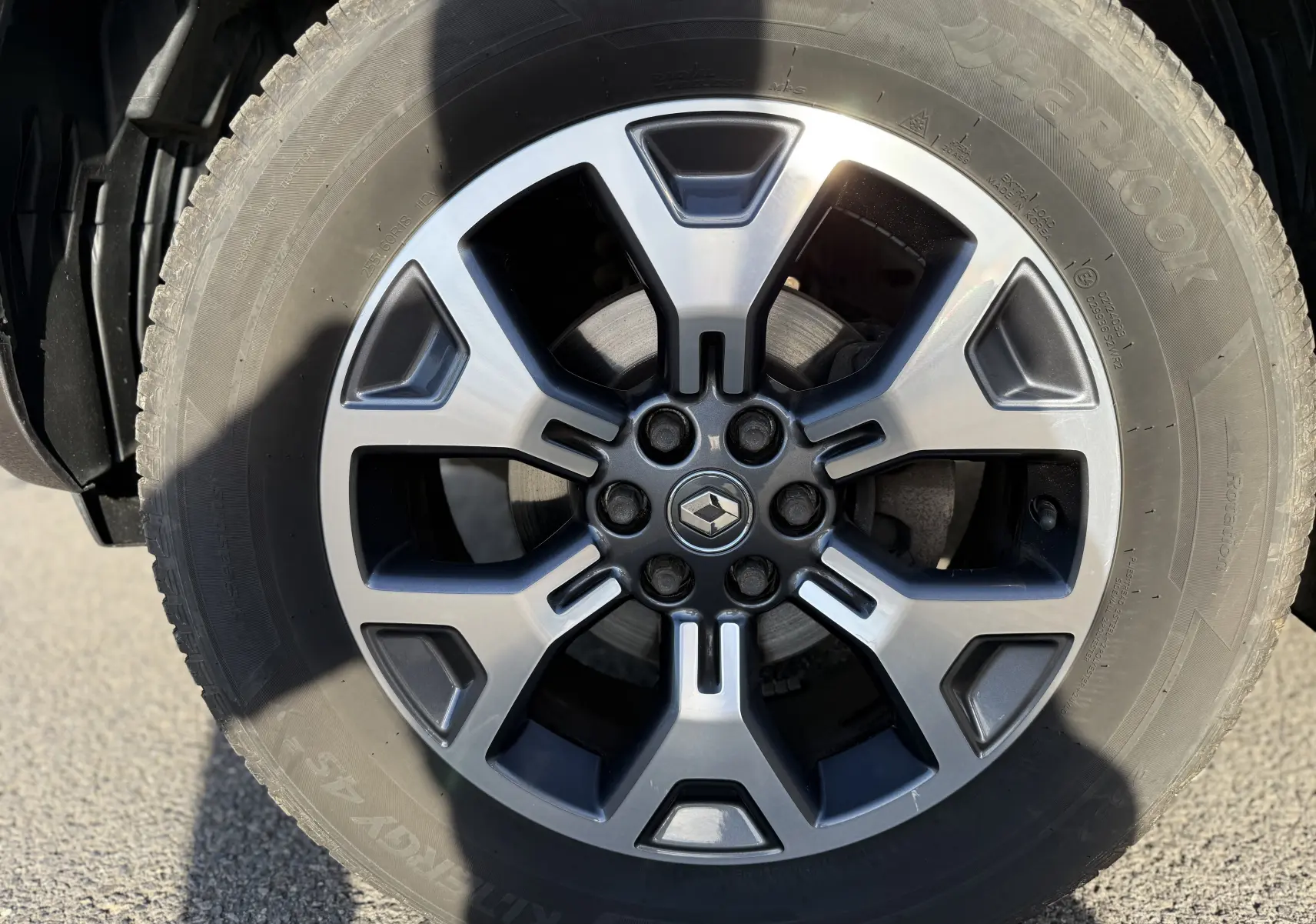 Gros plan sur la jante alliage grise et noire du Renault Alaskan brun, mettant en valeur le logo central et le pneu Hankook.