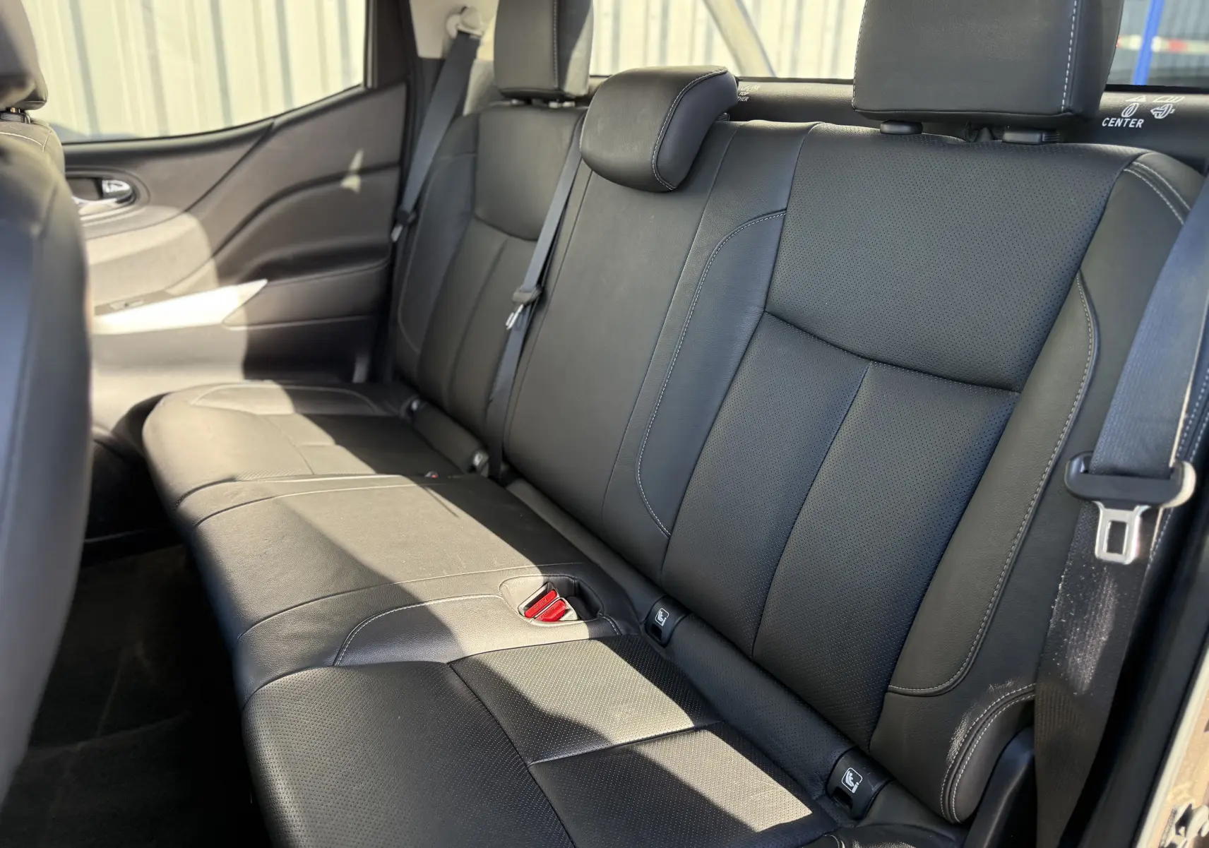 Vue intérieure du siège arrière en cuir noir du Renault Alaskan 2018, côté gauche avec ceinture de sécurité visible.