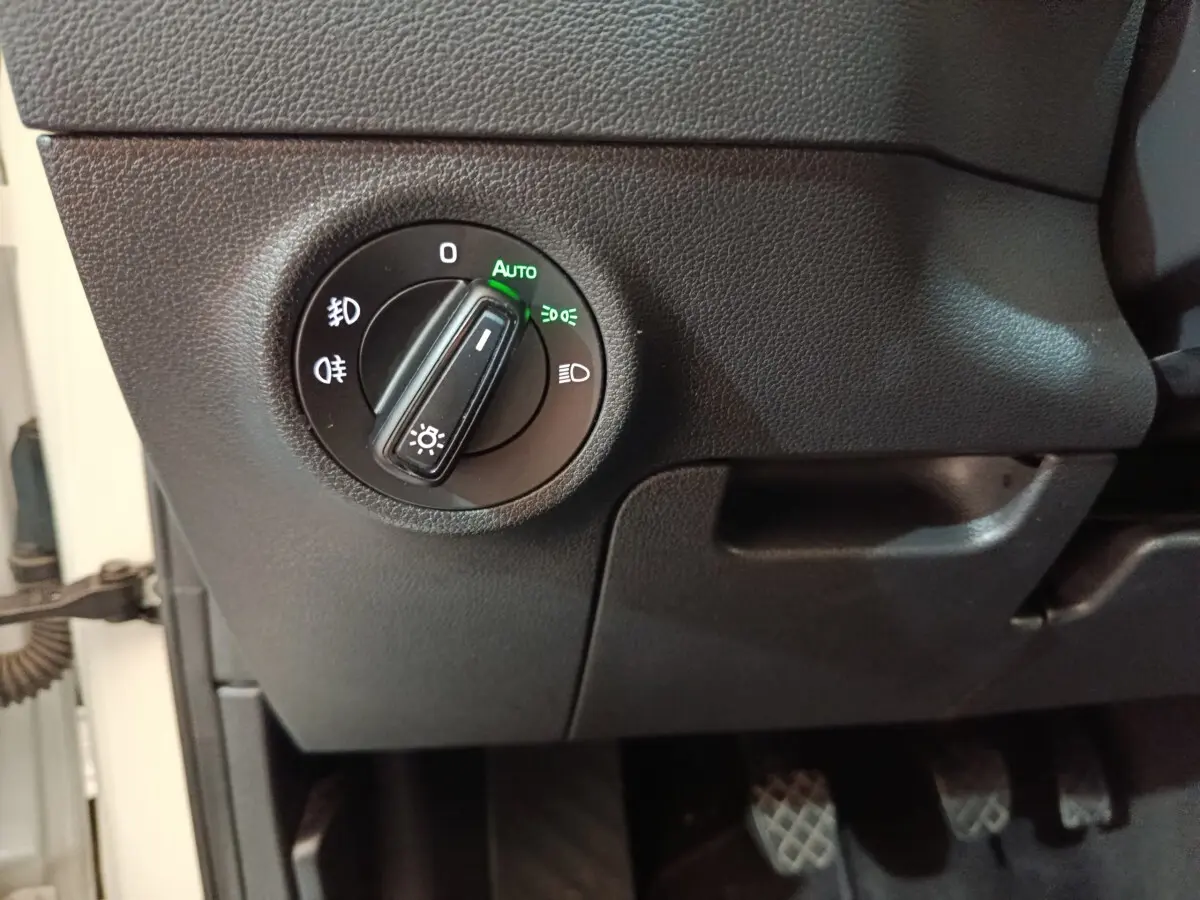 Gros plan sur la commande d’éclairage avec mode automatique activé dans le tableau de bord d’un Skoda Karoq blanc 2024.