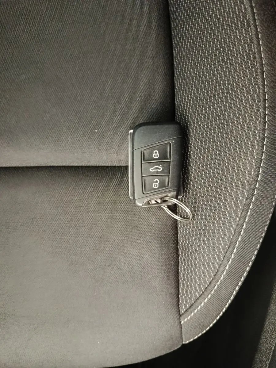 Clé de contact noire posée sur un siège tissu gris foncé à coutures blanches, intérieur d'un Skoda Karoq 2024.