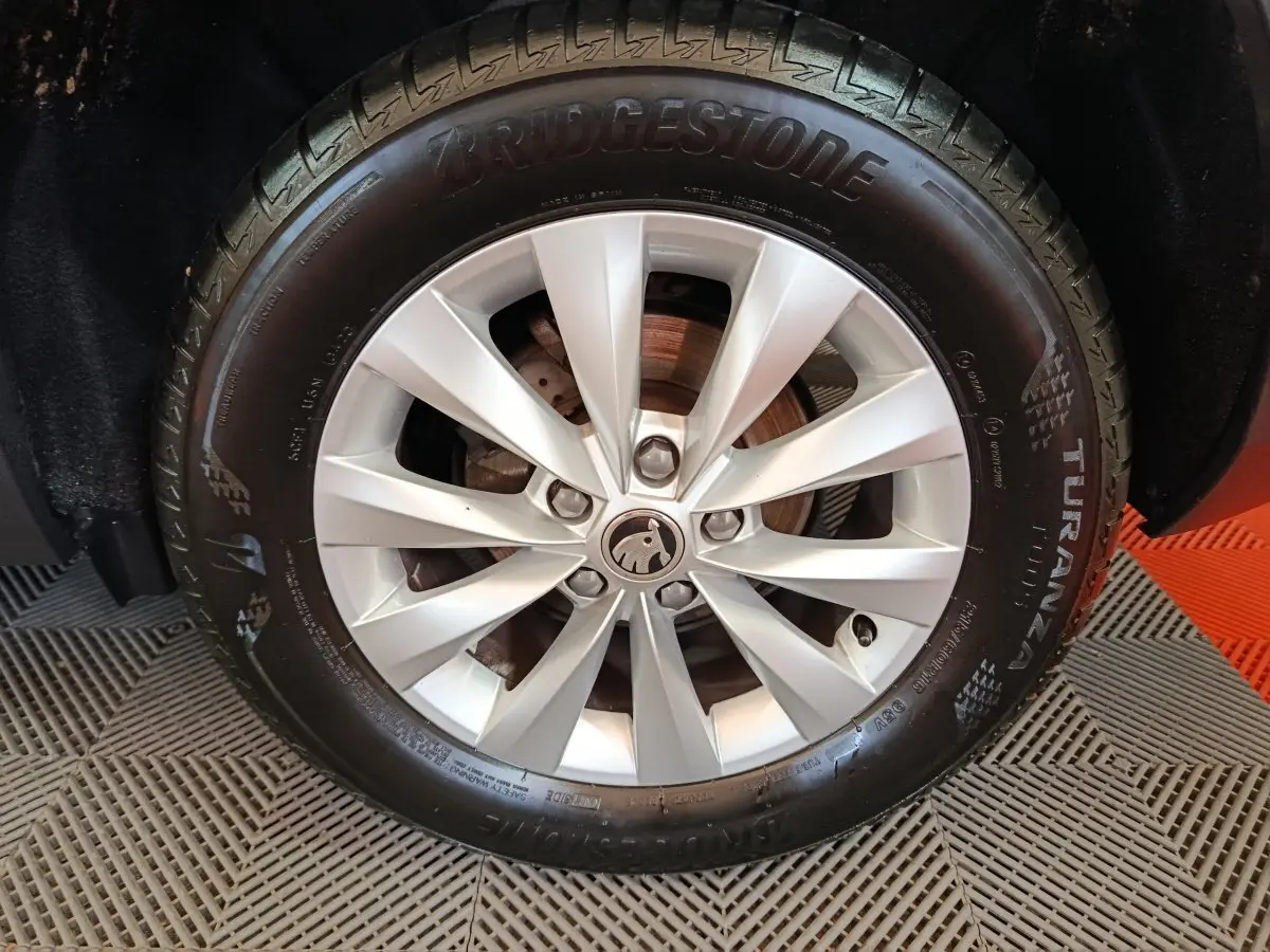 Gros plan sur la roue avant droite d’un Skoda Karoq blanc avec jante alliage et pneu Bridgestone Turanza.