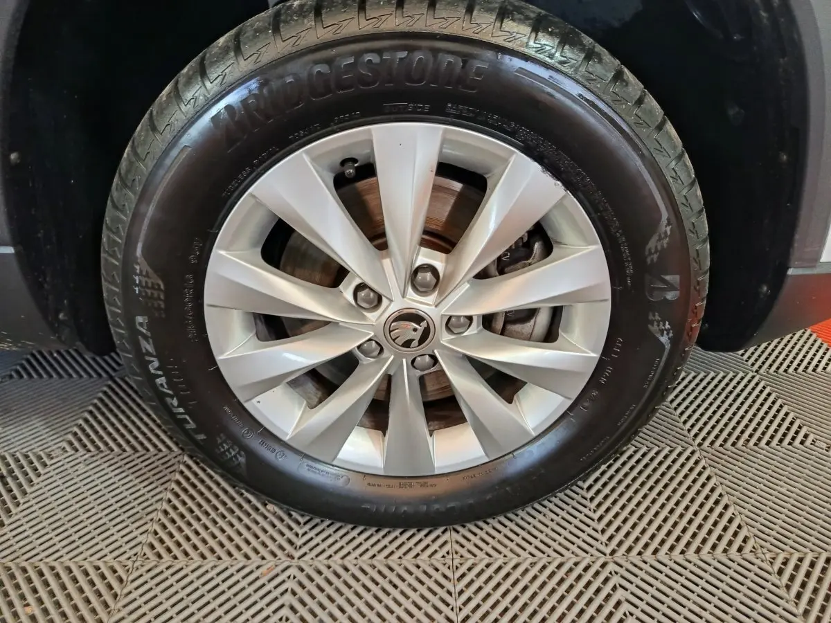 Gros plan sur la roue avant droite d’un Skoda Karoq blanc 2024 avec jante alliage et pneu Bridgestone.