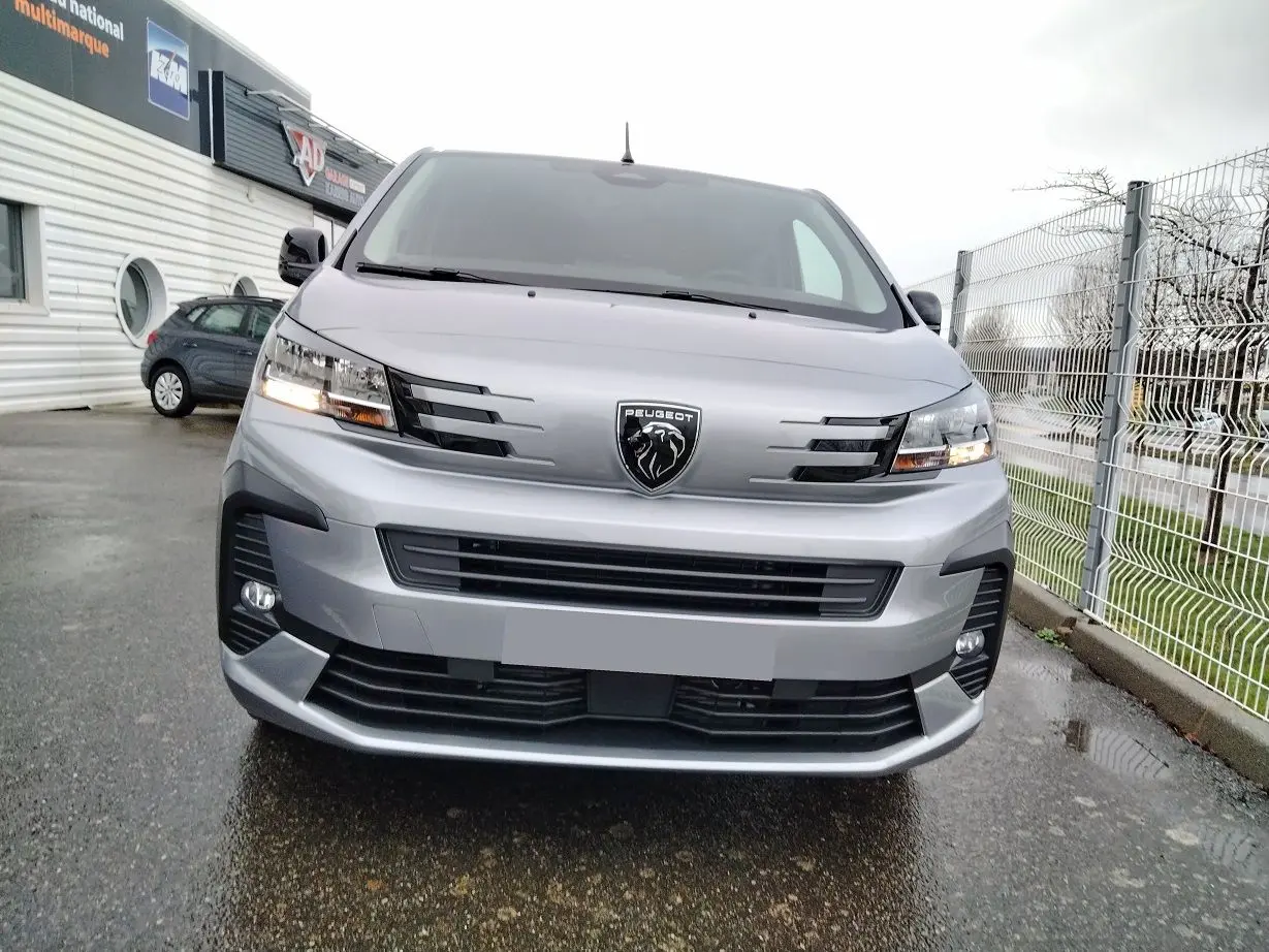 Vue frontale d'un Peugeot Expert Cabine Approfondie gris Artense avec calandre moderne et phares allumés.
