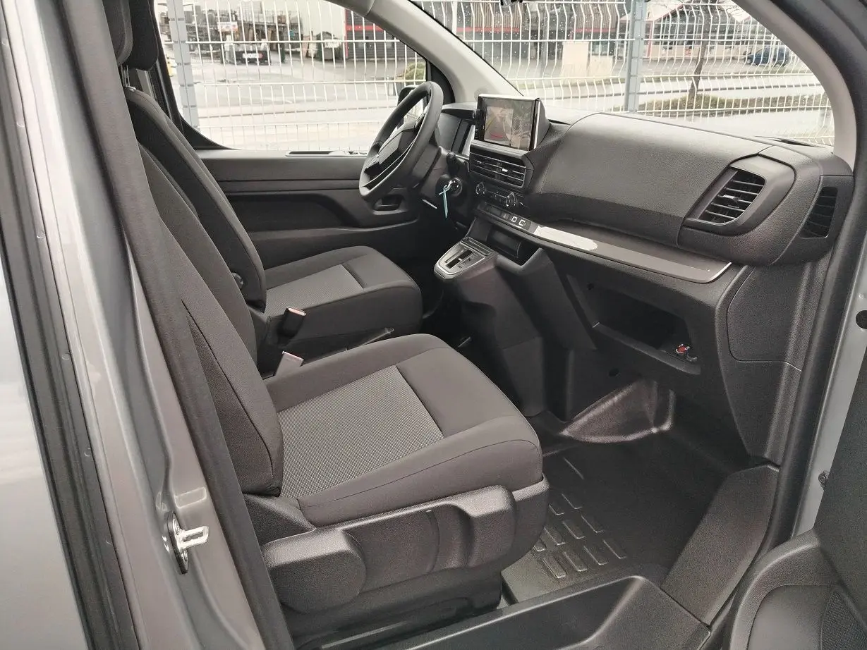 Vue intérieure côté conducteur du Peugeot Expert gris Artense, montrant les sièges tissu et le tableau de bord moderne avec écran central.