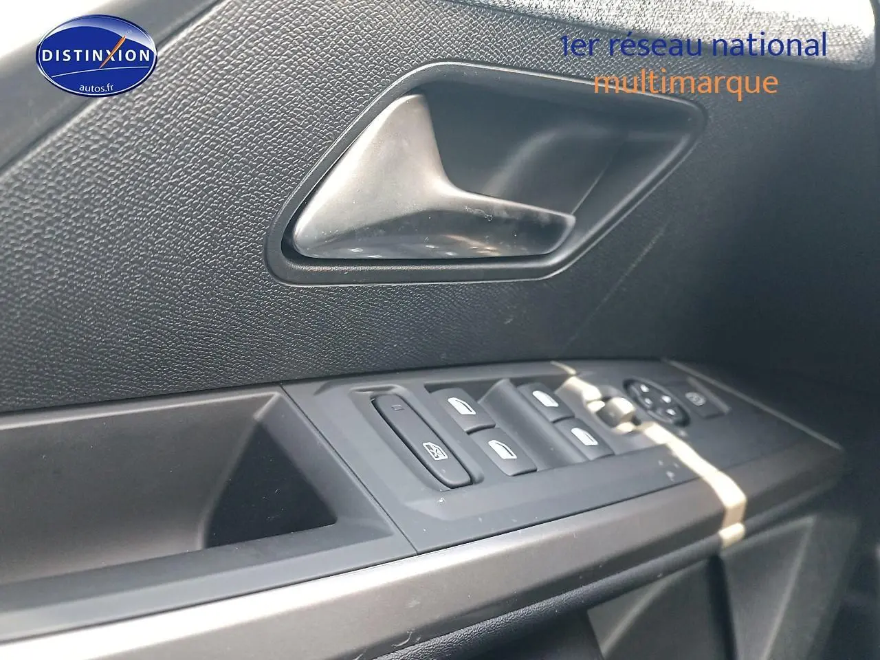 Gros plan sur la commande des vitres et la poignée intérieure côté conducteur d’une Peugeot 3008 bleu 2025.