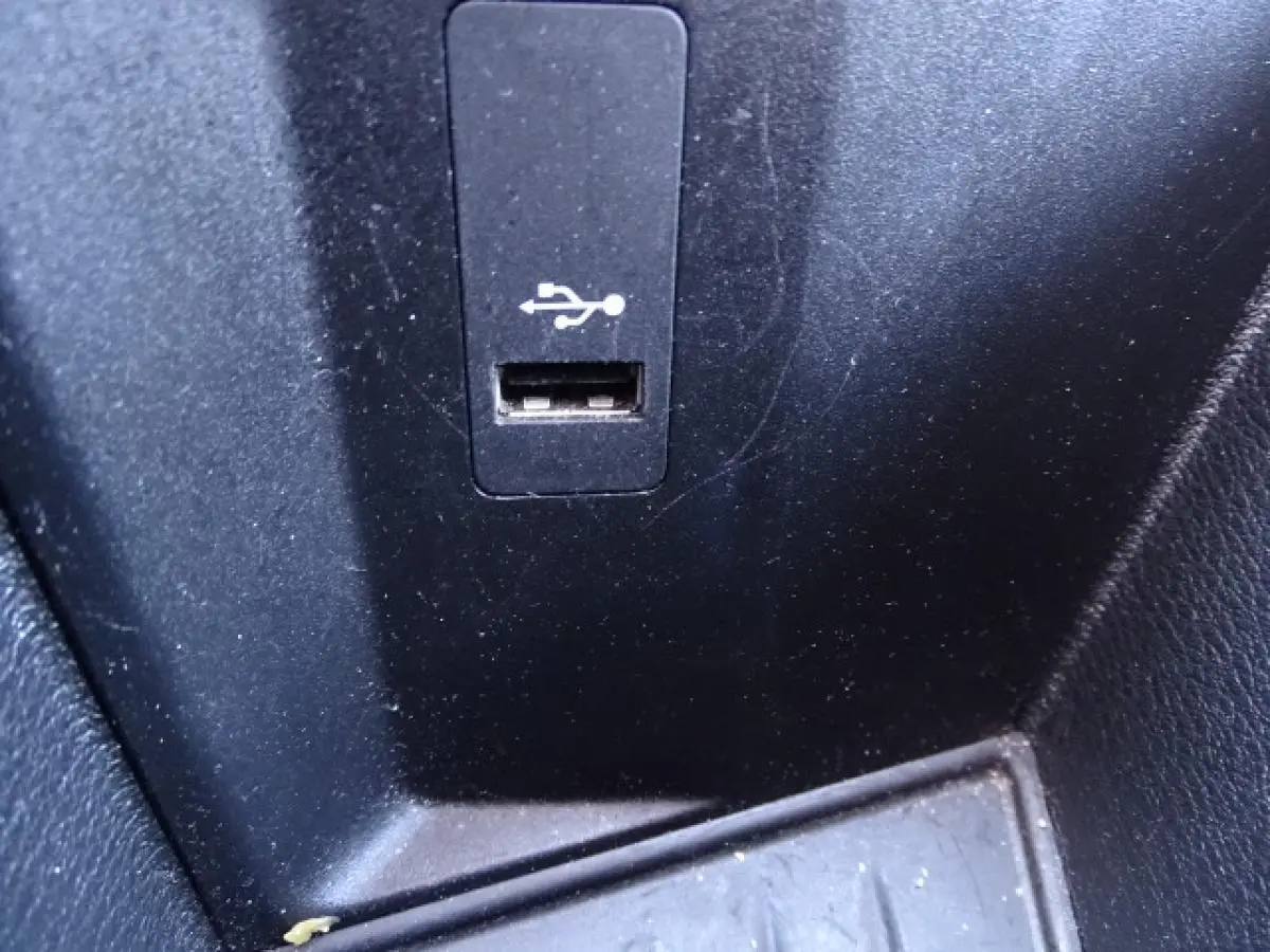 Gros plan sur le port USB intégré dans la console centrale noire d'un BMW X1 blanc.