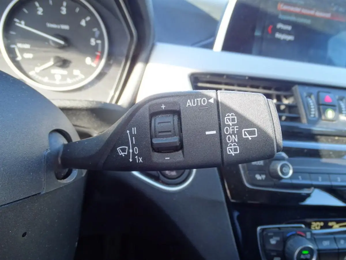 Gros plan sur la commande d’essuie-glace à gauche du volant dans l’habitacle d’un BMW X1 blanc de 2017.