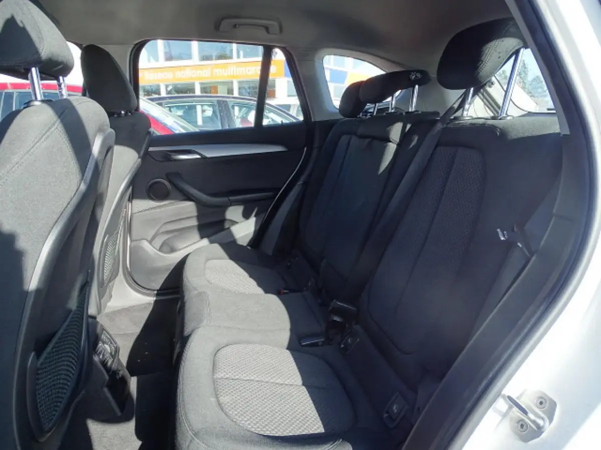Vue intérieure côté droit des sièges arrière en tissu noir d'une BMW X1 blanc 2017, avec appuis-tête ajustables.