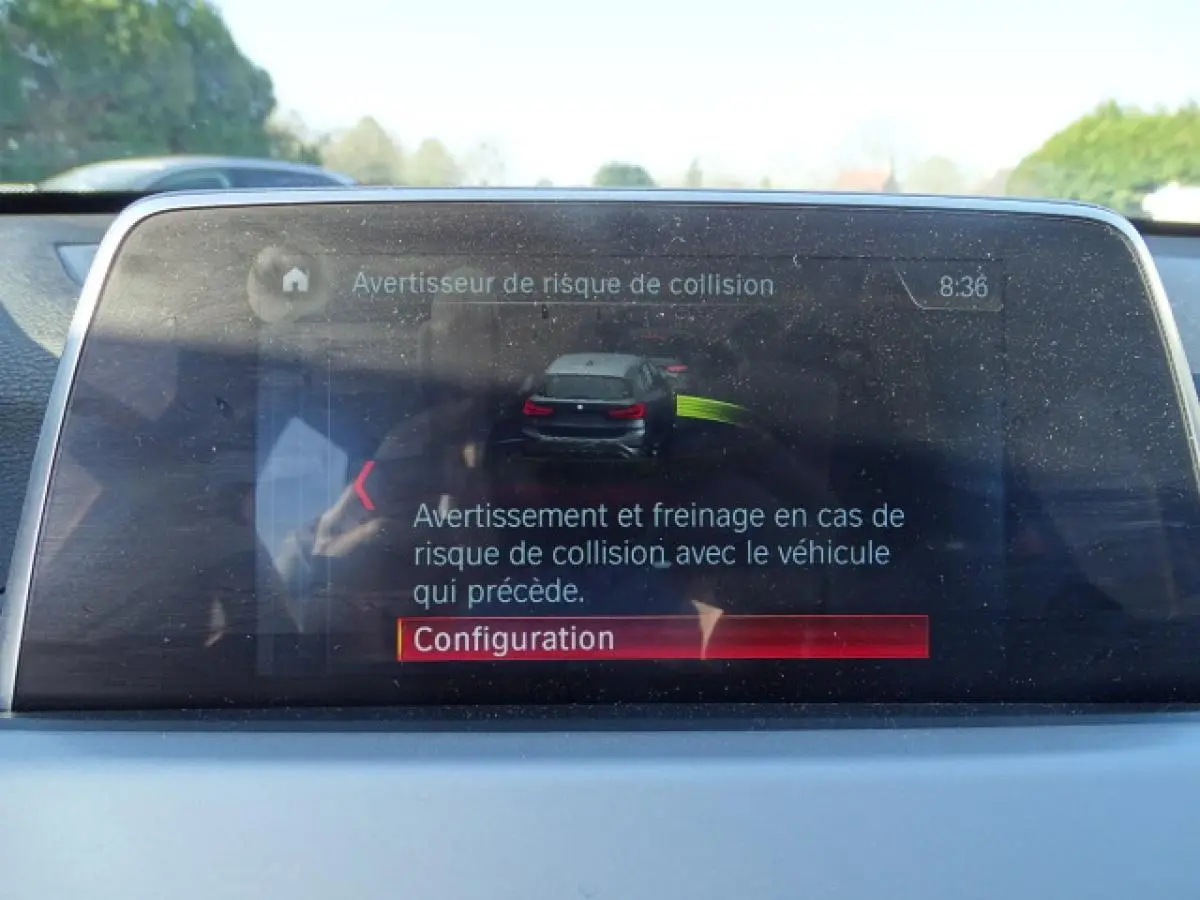 Écran central du BMW X1 blanc 2017 montrant l'alerte de risque de collision avec configuration en cours.