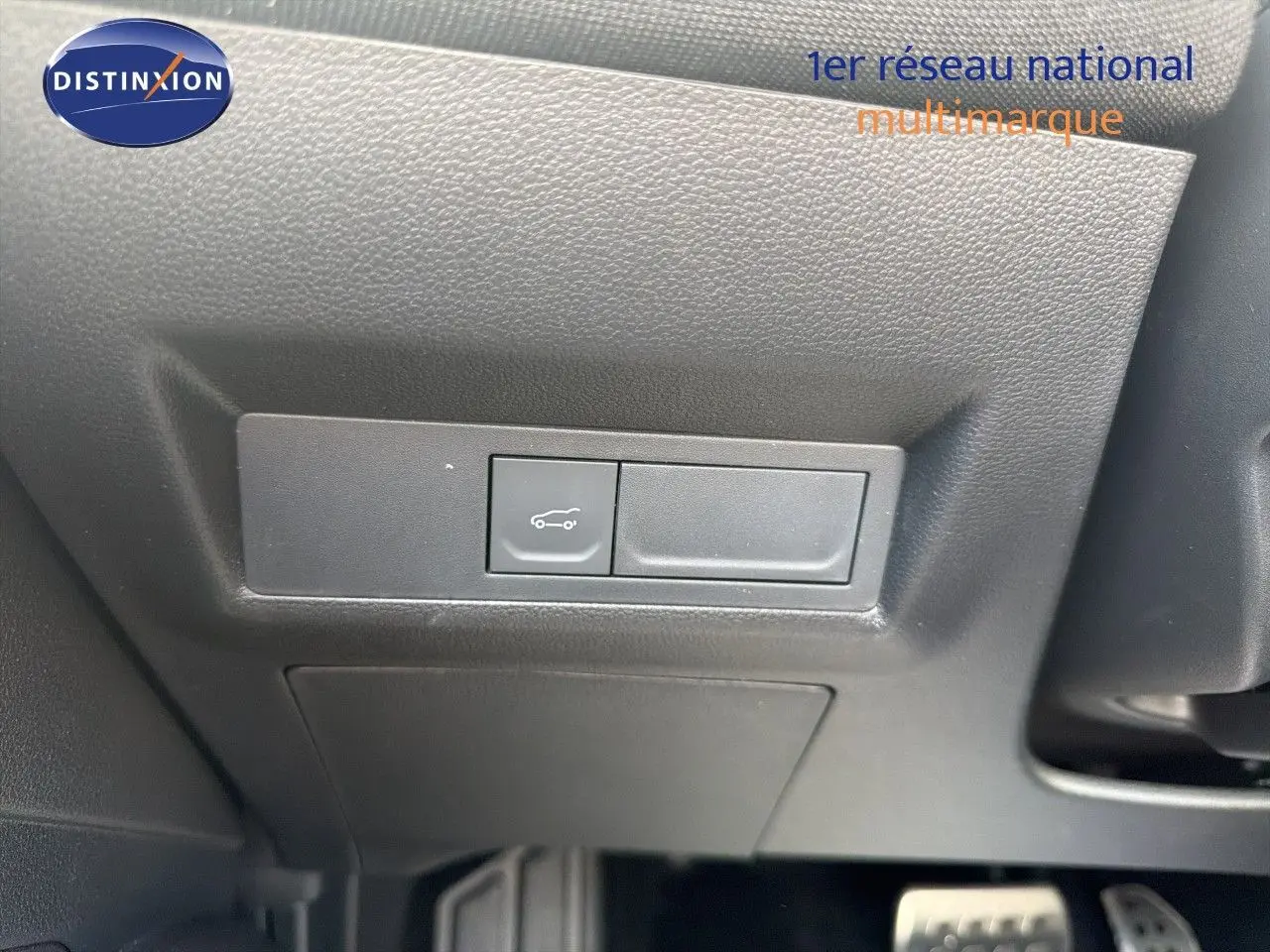 Bouton d'ouverture du coffre sur panneau noir sous le tableau de bord d'une Renault Symbioz gris cassiopée.