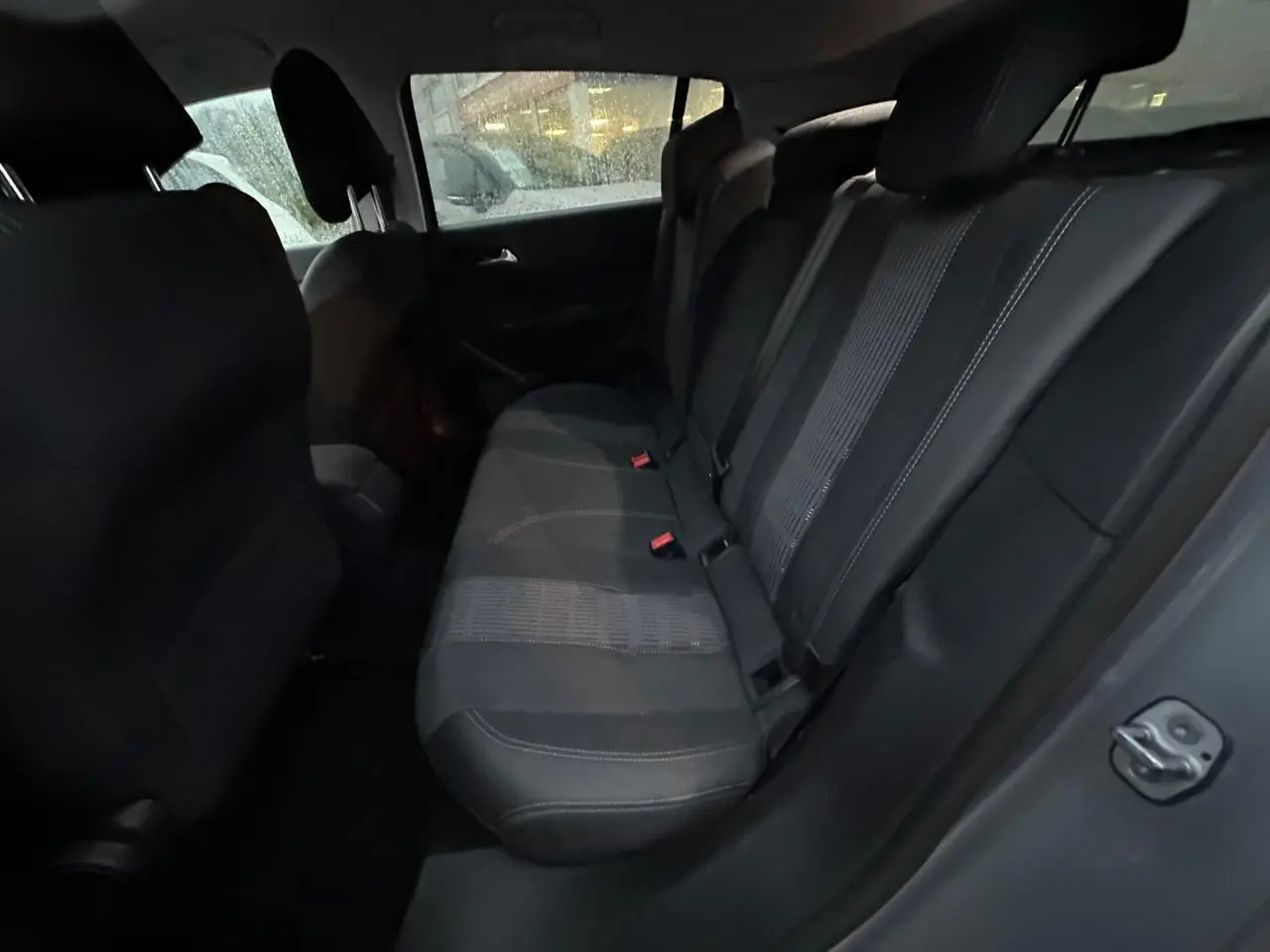 Vue intérieure du siège arrière droit de la Peugeot 308 gris Artense, montrant la banquette en tissu noir avec ceinture de sécurité.