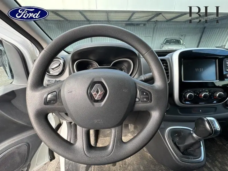 Vue intérieure centrée sur le volant Renault d'un Trafic blanc avec tableau de bord et console multimédia visible.