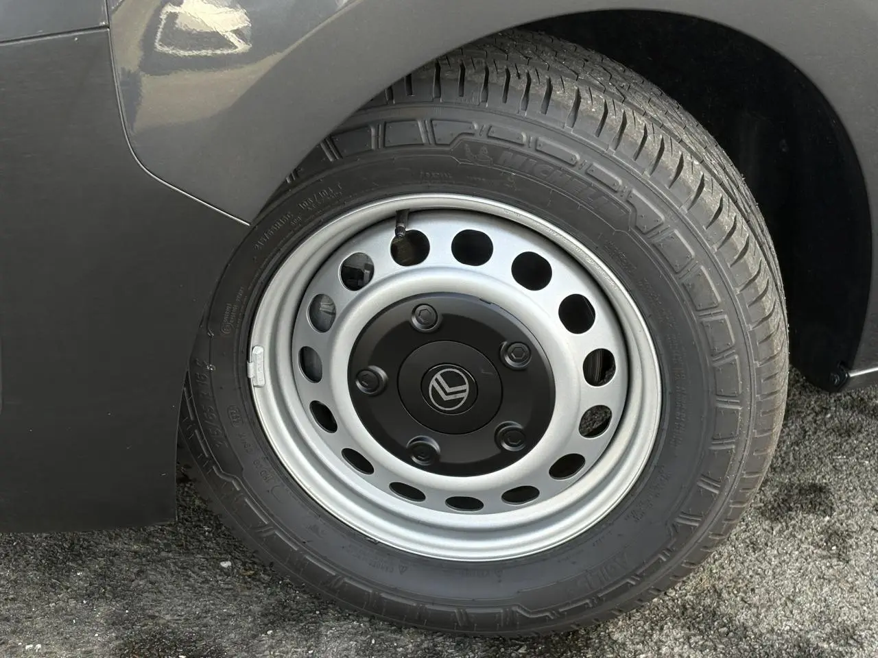 Gros plan sur la roue arrière droite d’un Citroën Jumpy gris titane avec jante acier et logo Citroën au centre.