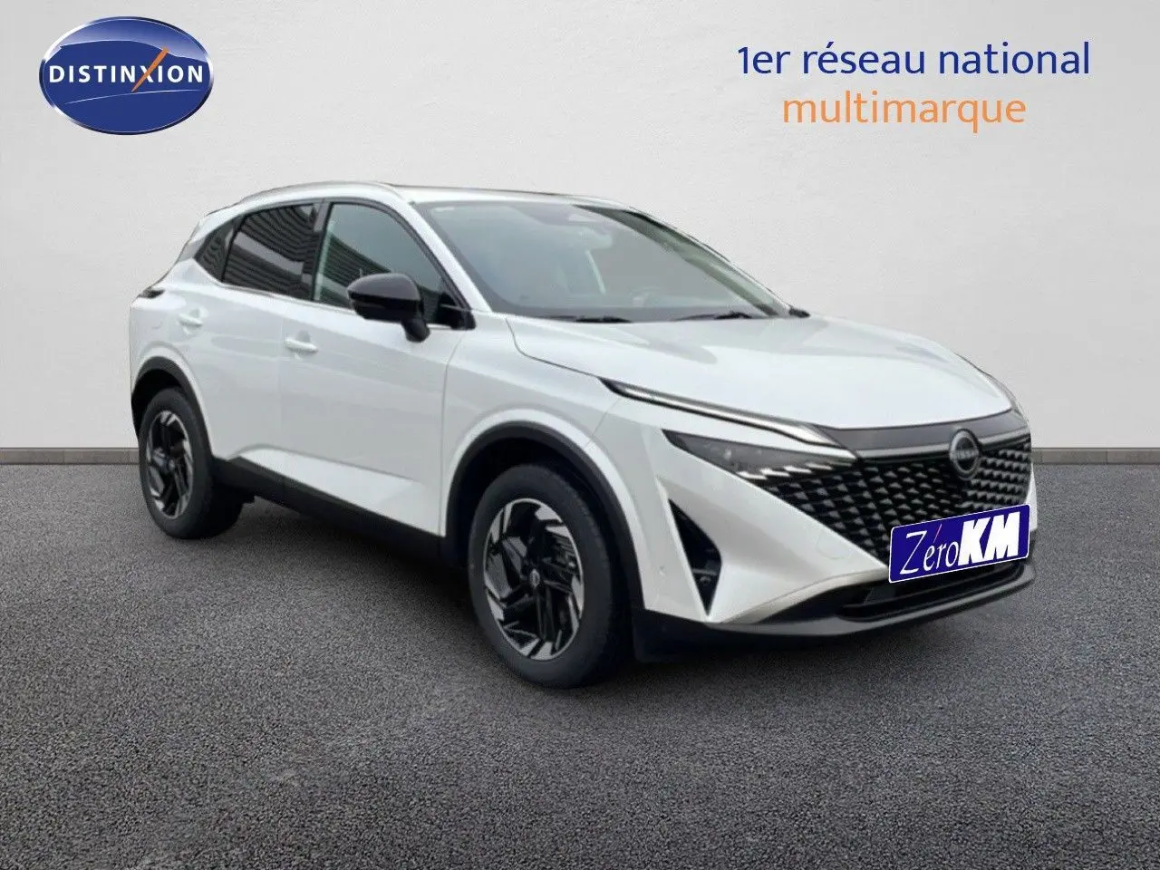 Nissan Qashqai blanc nacré métal en 3/4 avant droit, avec calandre noire et jantes bi-ton distinctives.