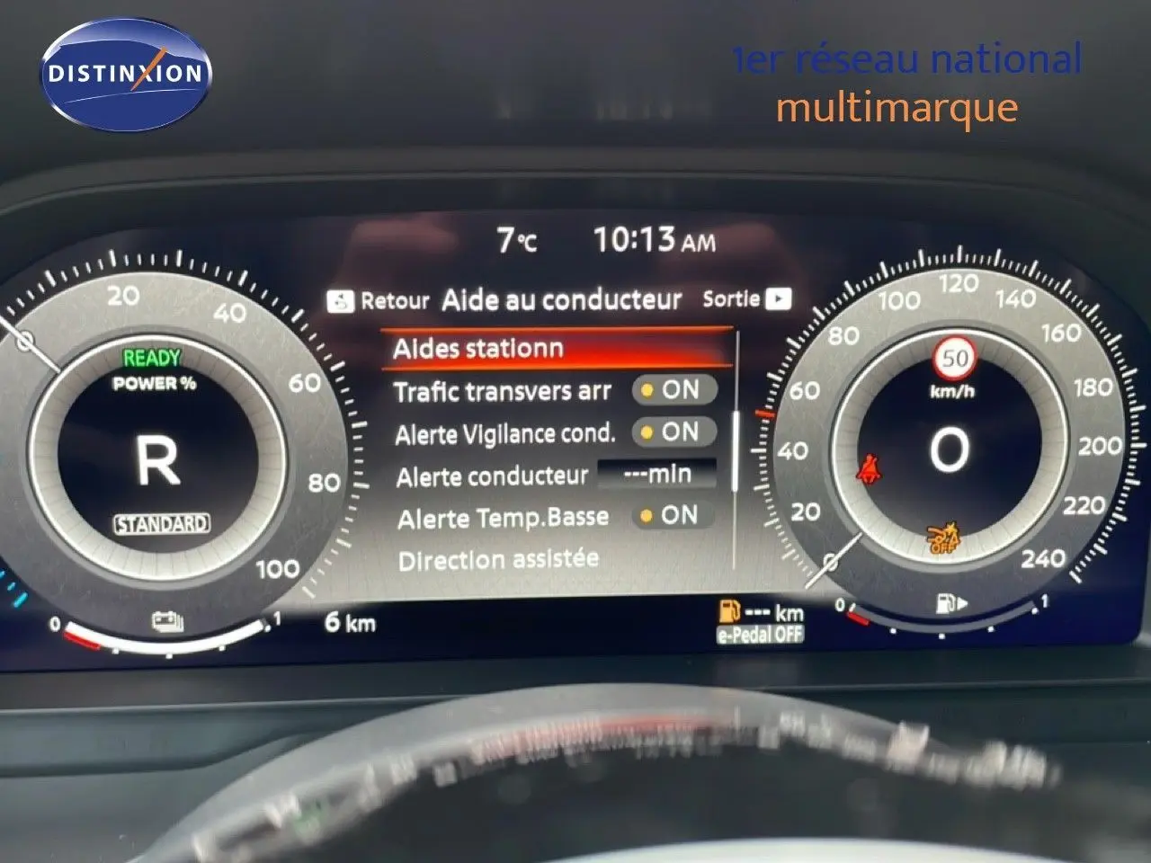 Tableau de bord numérique du Nissan Qashqai blanc nacré, affichant les aides à la conduite et la vitesse à 0 km/h.