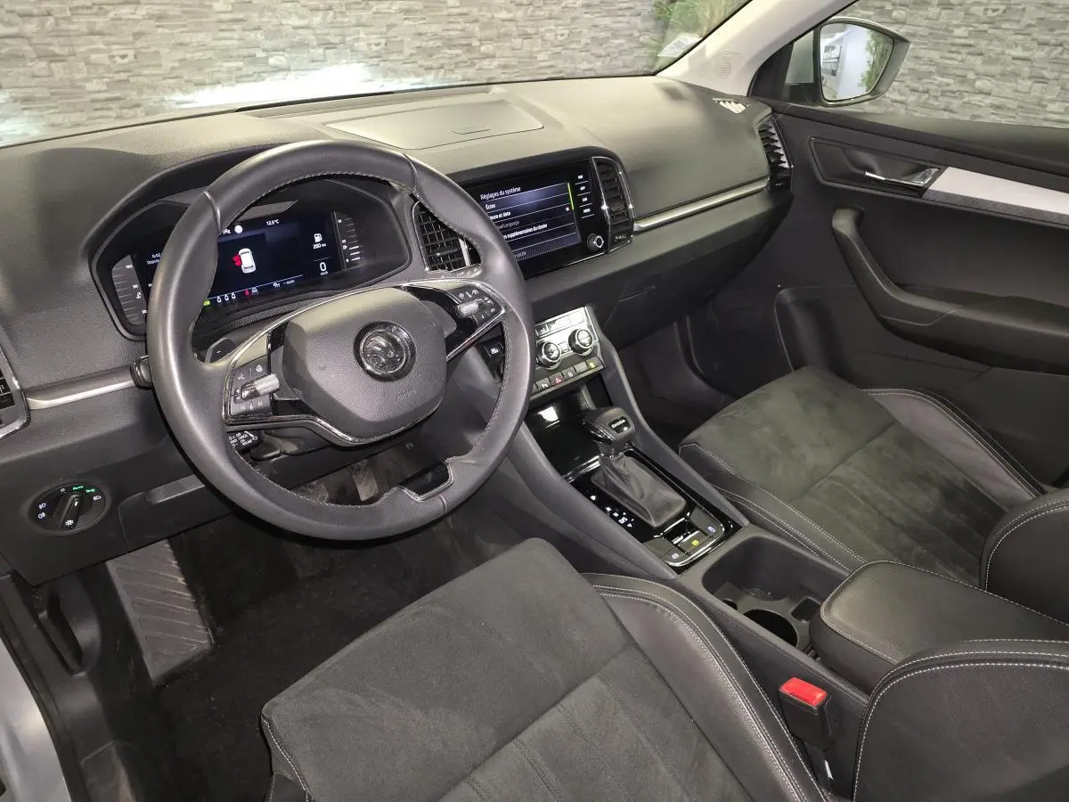 Intérieur avant droit du Skoda Karoq 2023 gris, volant cuir multifonction et console centrale avec écran tactile.