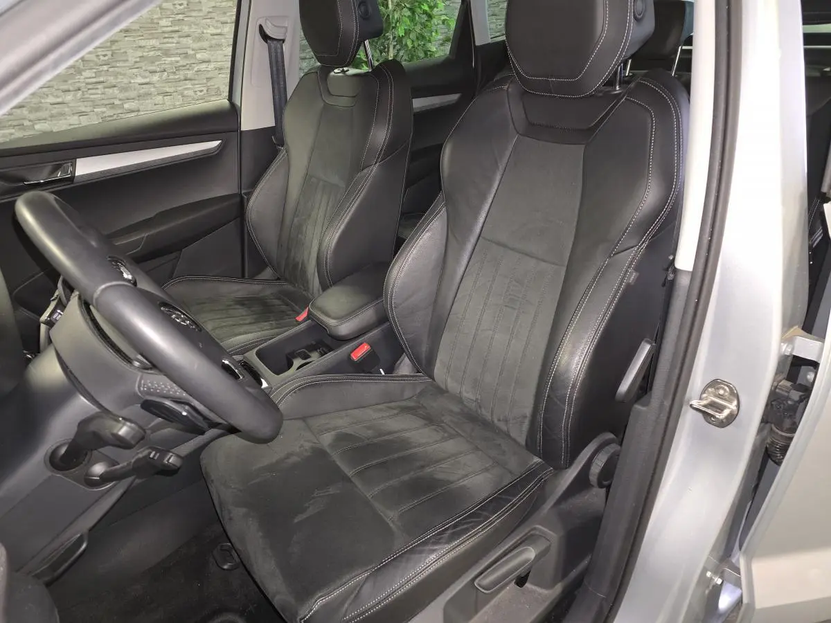 Vue intérieure côté conducteur du Skoda Karoq 2023, sièges en cuir noir avec surpiqûres blanches et volant multifonction.