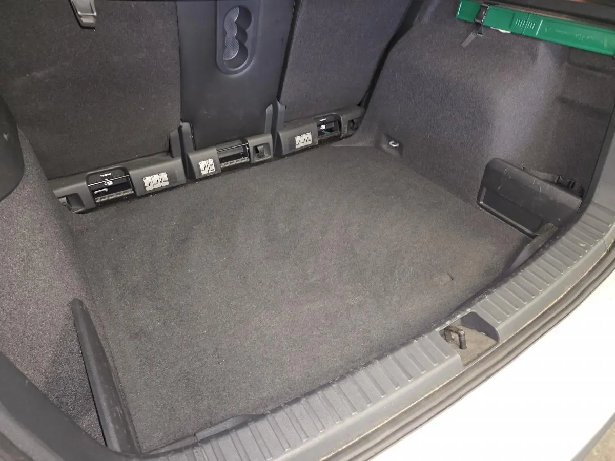 Vue intérieure du coffre spacieux et propre du Skoda Karoq gris, montrant les fixations ISOFIX arrière et les finitions en tissu noir.