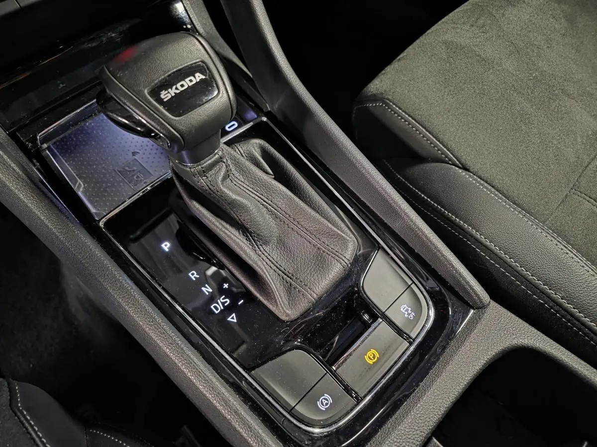 Gros plan sur le levier de vitesse en cuir noir et le chargeur à induction dans la console centrale du Skoda Karoq 2023.