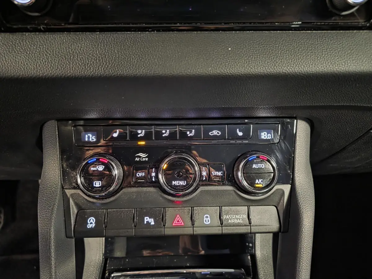 Gros plan sur la console centrale noire du Skoda Karoq 2023 avec commandes climatisation et boutons fonctionnels.