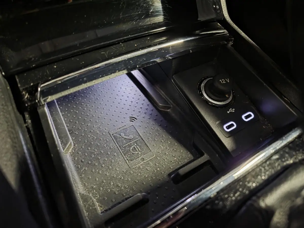 Gros plan sur le chargeur à induction et prises USB-C éclairées dans la console centrale du Skoda Karoq gris 2023.