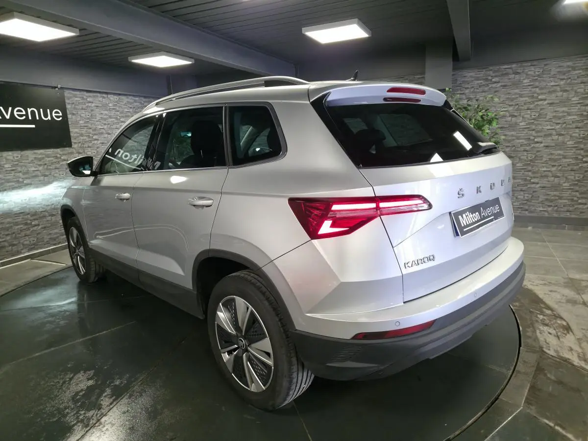 Vue 3/4 arrière droite d'un Skoda Karoq gris 2023 avec feux arrière LED et jantes alliage 17 pouces.