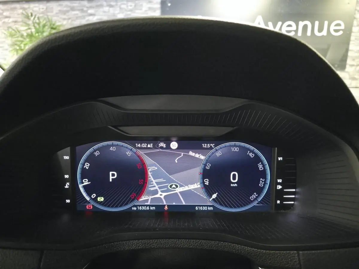 Vue du tableau de bord numérique du Skoda Karoq gris 2023, affichant la navigation et les compteurs digitaux.