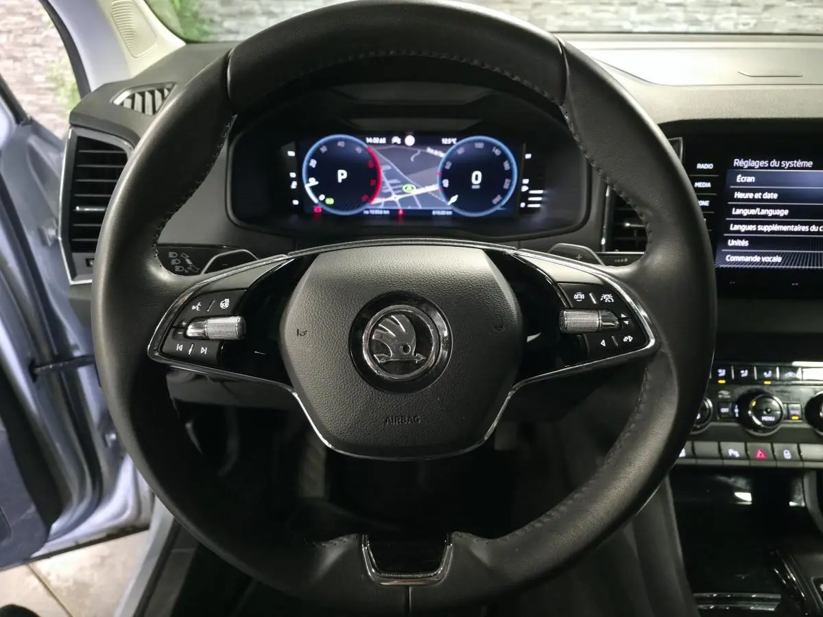 Vue rapprochée du volant cuir noir du Skoda Karoq 2023 avec tableau de bord numérique et écran tactile latéral.