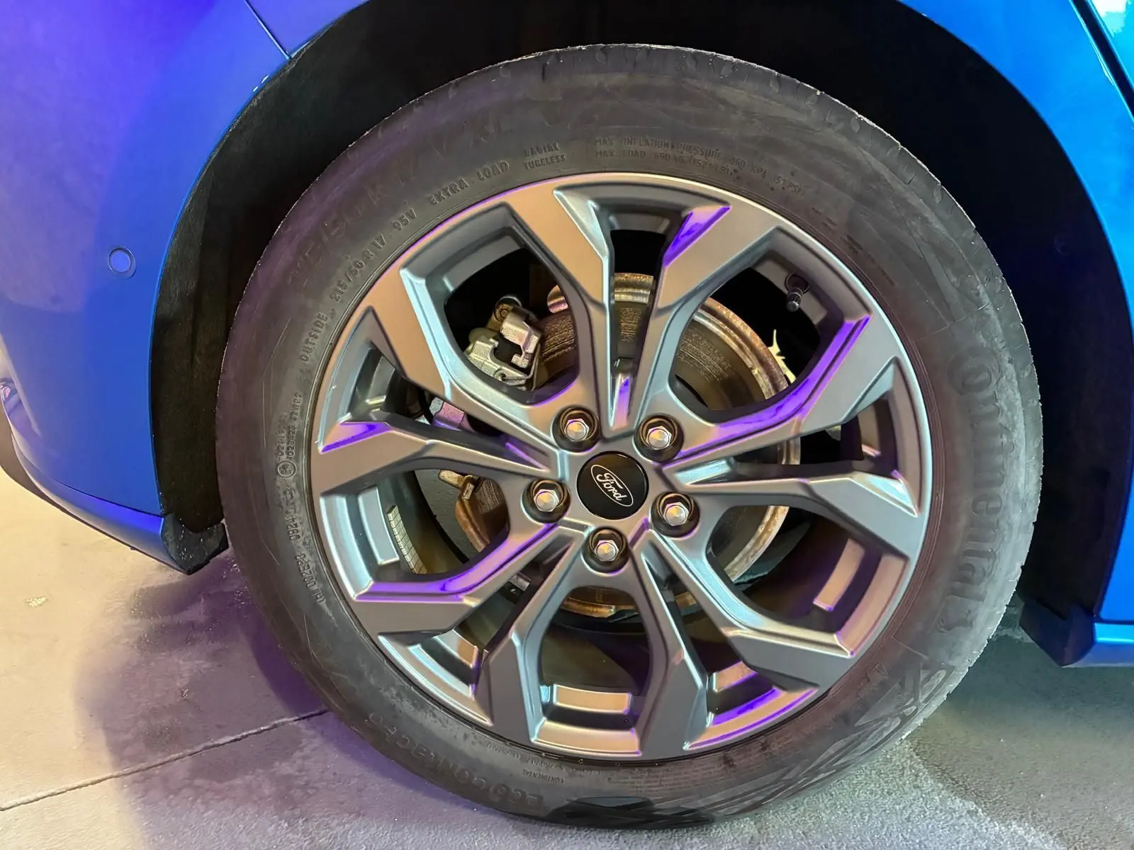Gros plan sur la roue avant gauche de la Ford Focus 2024 bleu, avec jante alliage au design moderne et logo Ford central.