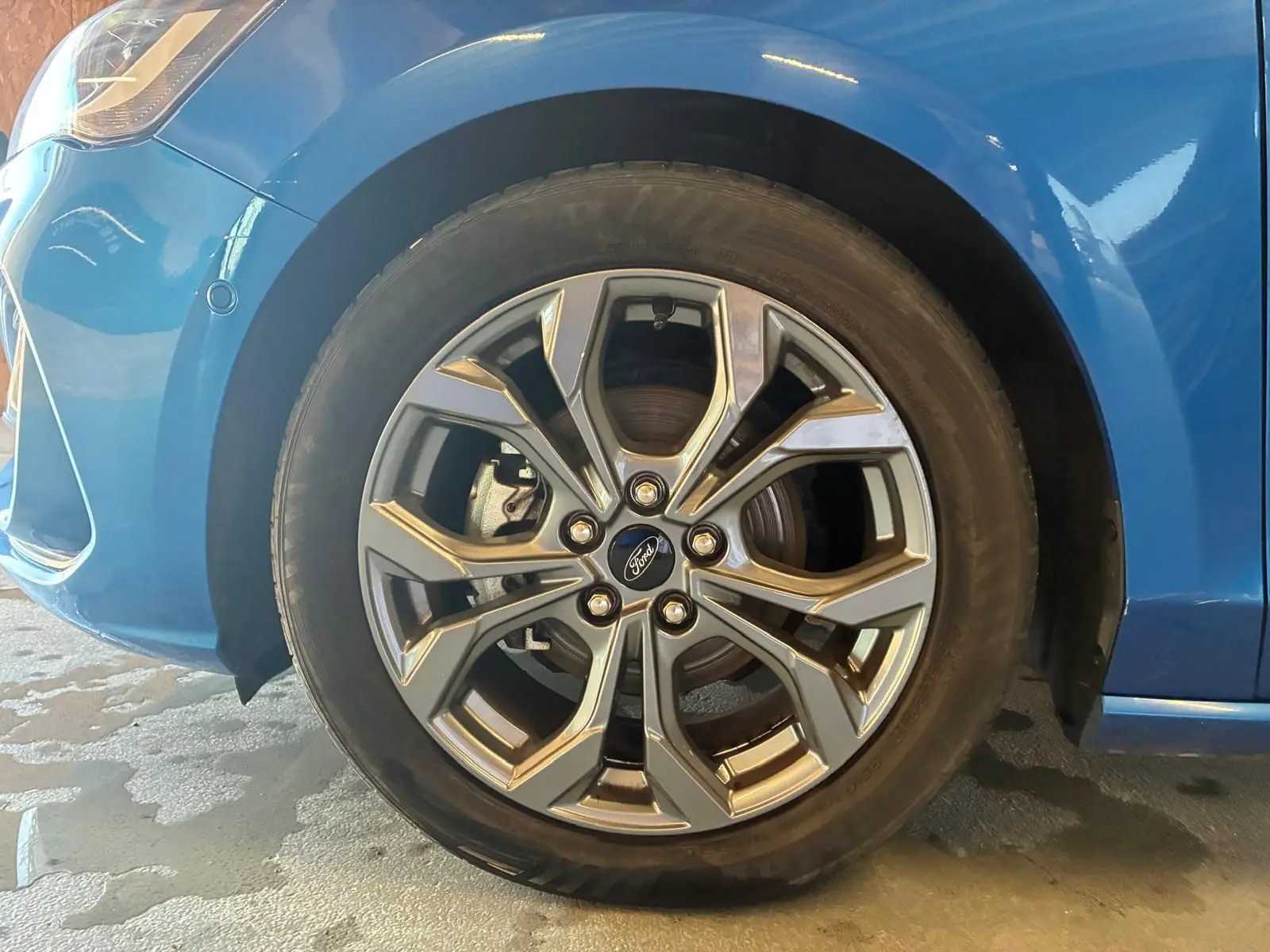 Gros plan sur la roue avant gauche de la Ford Focus bleue 2024 avec jante alliage au design moderne.