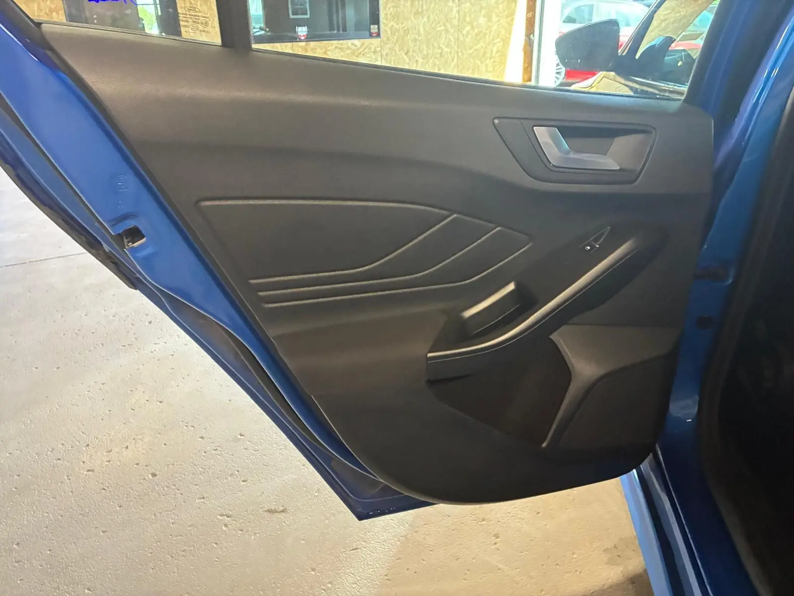Vue intérieure de la porte arrière gauche bleu de la Ford Focus 2024, avec habillage noir et poignée intégrée.