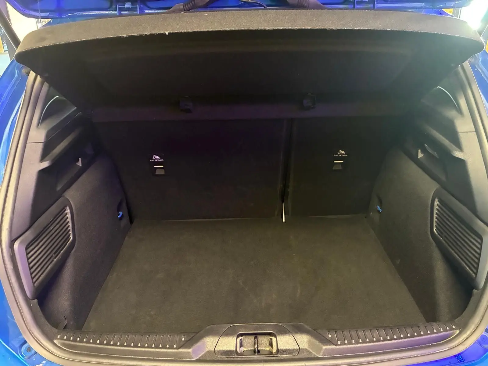 Coffre ouvert de la Ford Focus 2024 bleu, vue arrière montrant l’espace de chargement et les finitions intérieures noires.