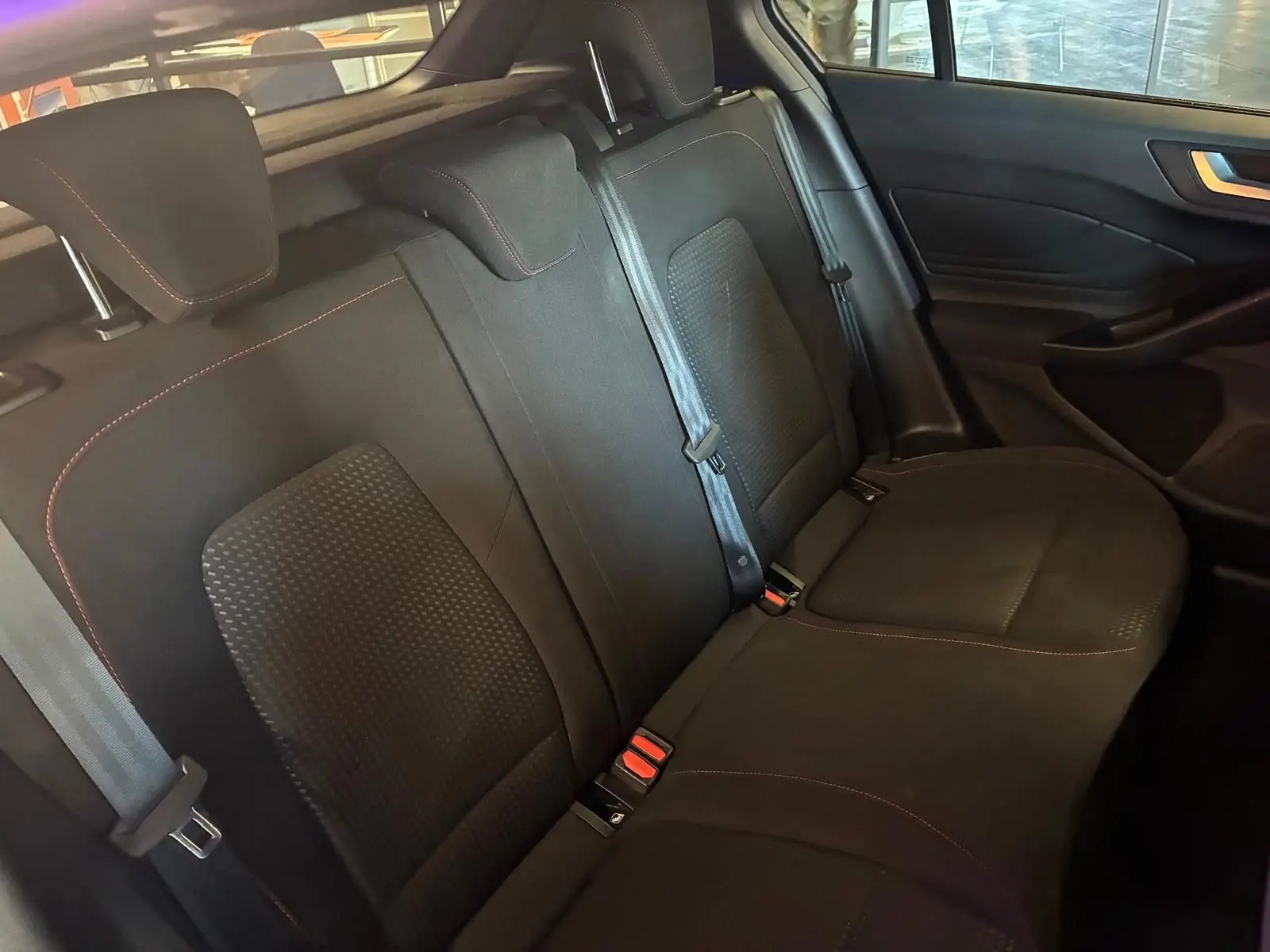 Vue intérieure côté droit des sièges arrière noirs en tissu avec surpiqûres rouges de la Ford Focus 2024.