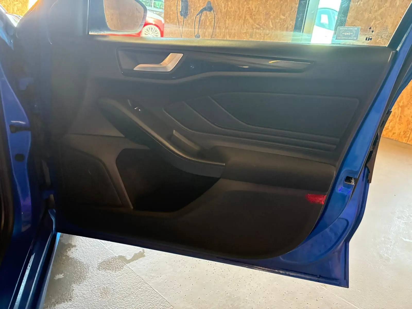 Vue intérieure de la porte avant gauche bleu vif d'une Ford Focus 2024, avec panneau noir et poignée argentée.