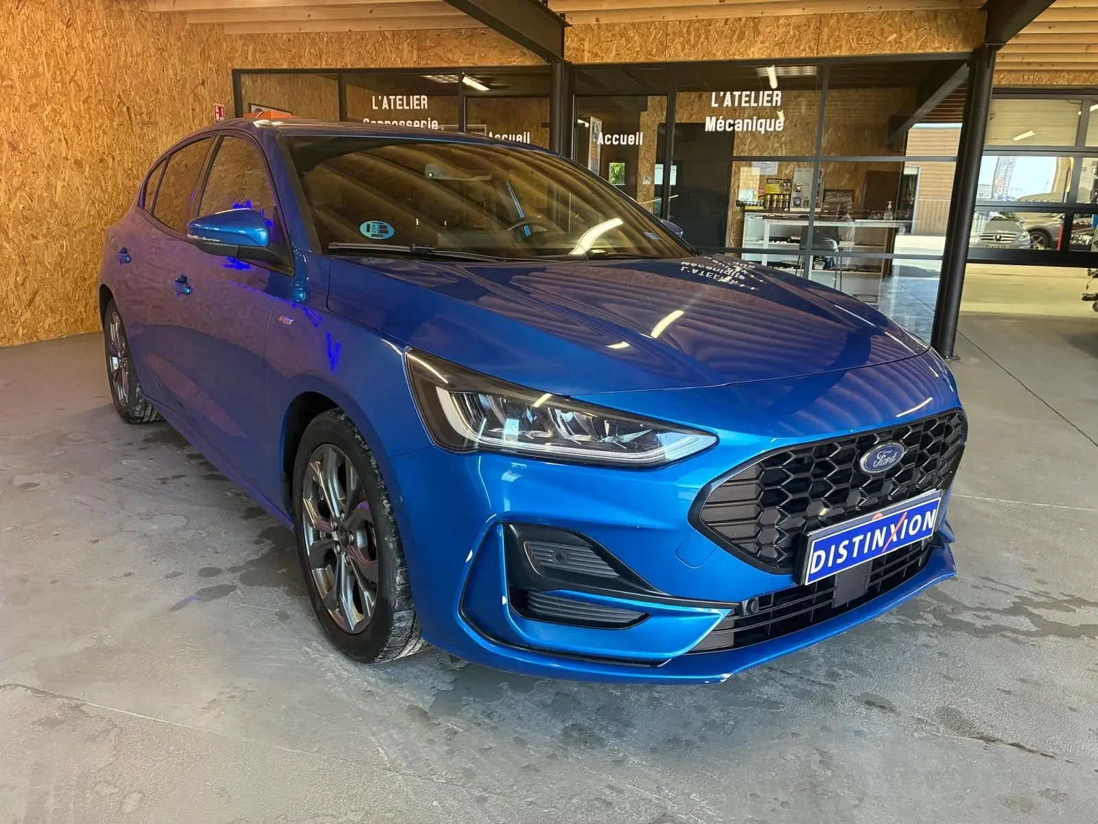 Ford Focus 1.0 EcoBoost hybride bleu en 3/4 avant droit, avec calandre noire et phares LED distinctifs.