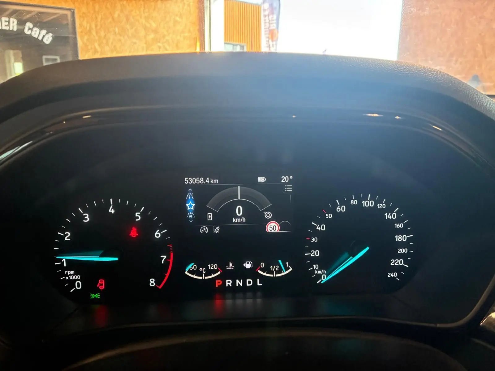 Tableau de bord numérique de Ford Focus bleu 2024, affichant vitesse à 0 km/h et indicateurs de température et carburant.