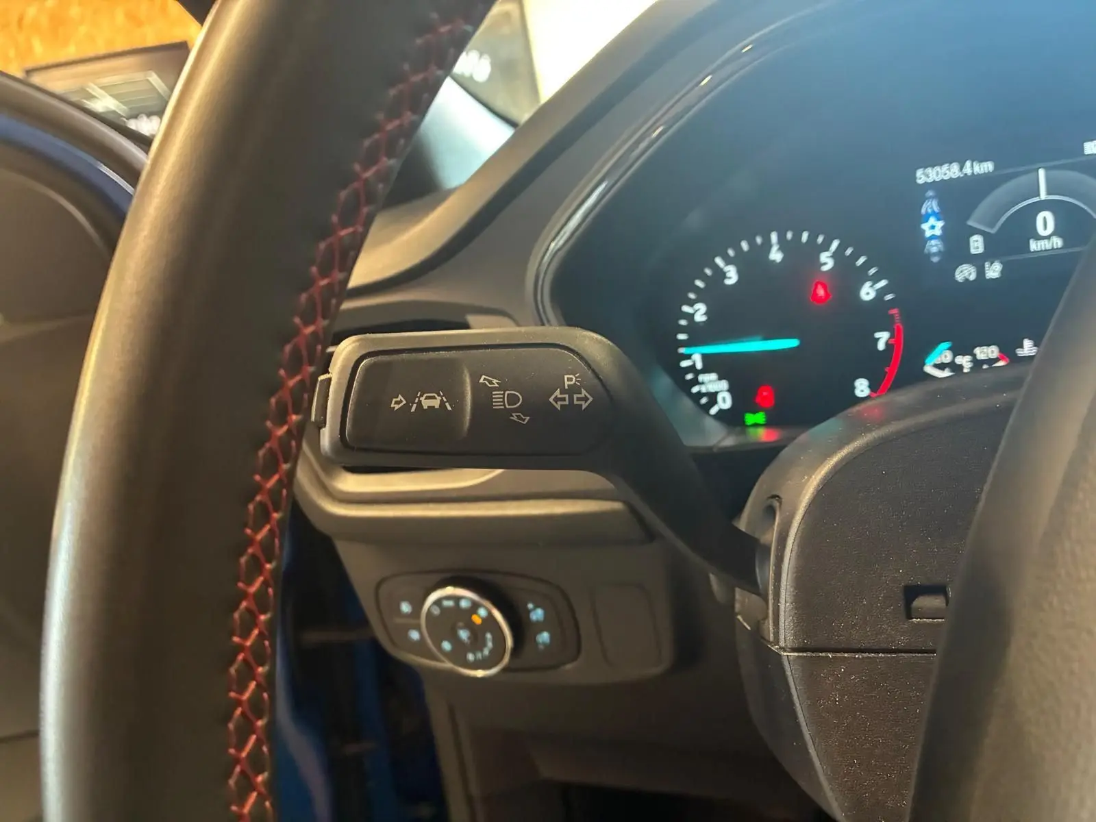 Vue rapprochée du commodo gauche et du tableau de bord numérique d’une Ford Focus bleue 2024, intérieur noir.
