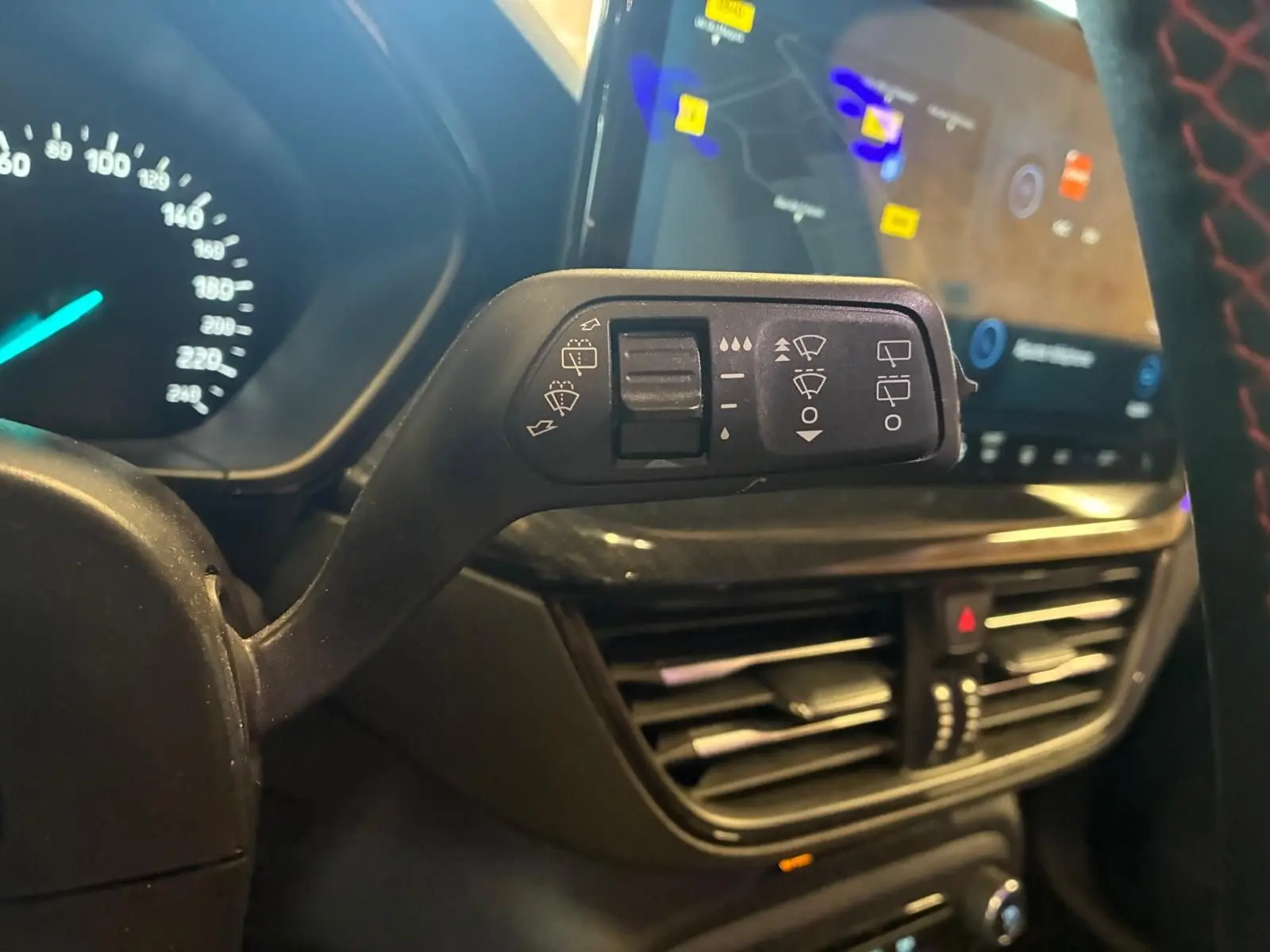 Gros plan sur la commande d’essuie-glace à gauche du volant dans l’habitacle noir de la Ford Focus bleu 2024.