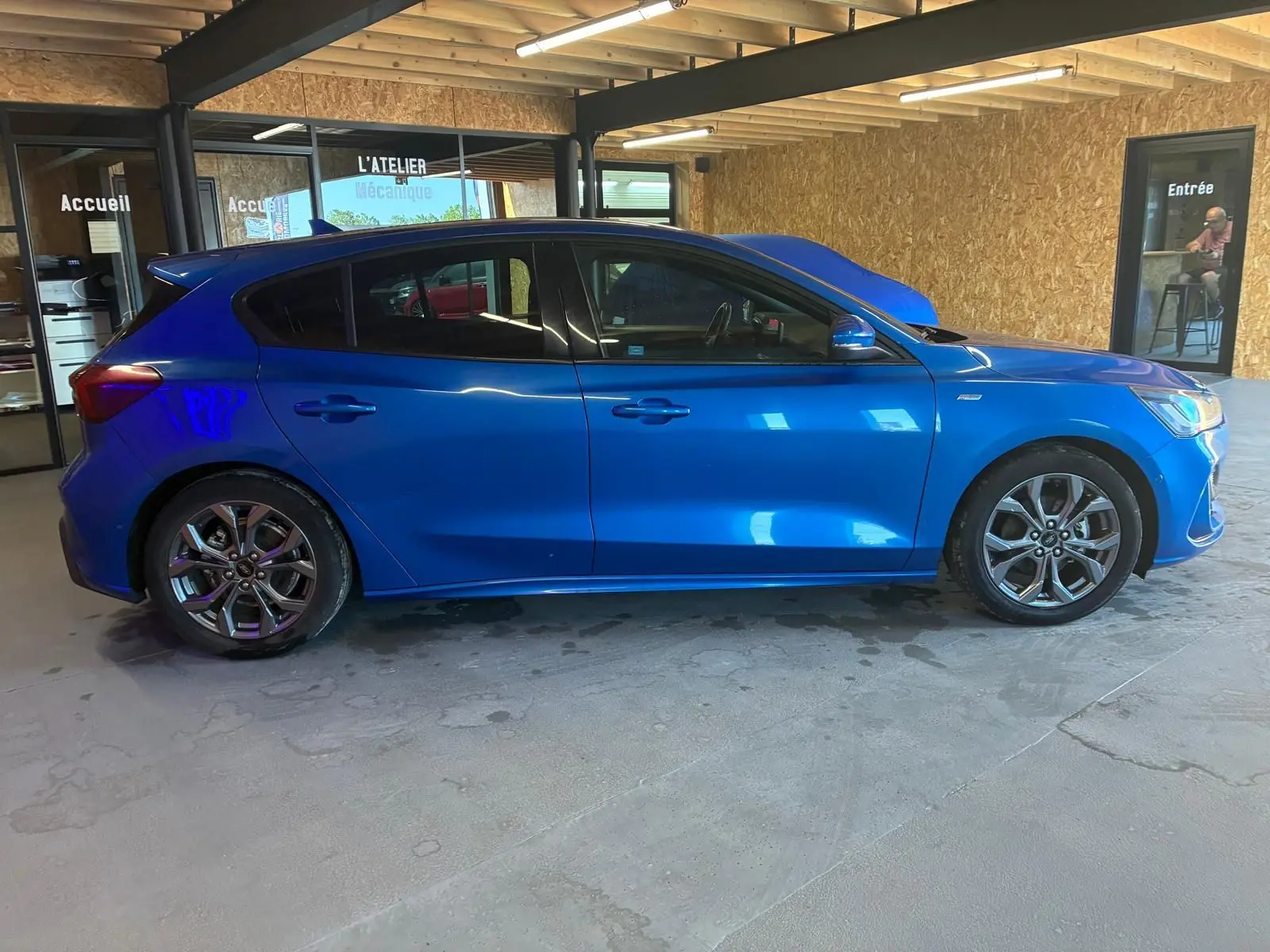 Vue de profil côté gauche d'une Ford Focus 2024 bleu vif, finition ST Line avec jantes alliage et vitres teintées.