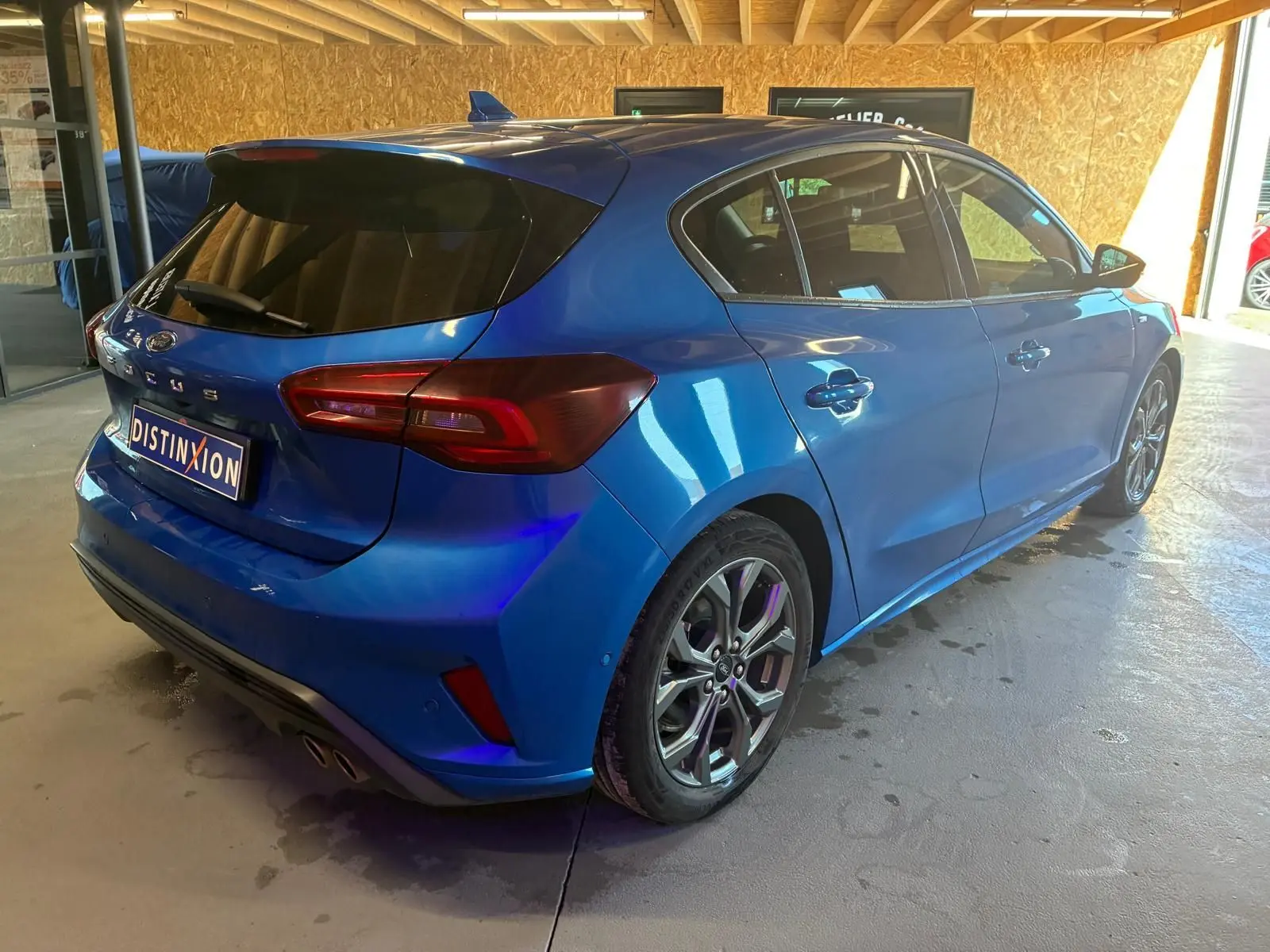 Vue 3/4 arrière droite d'une Ford Focus bleue 5 portes avec feux arrière LED et jantes alliage.