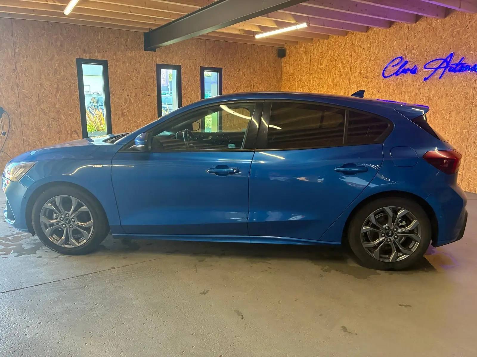Vue de profil côté gauche d'une Ford Focus bleu 2024 en finition ST Line, avec jantes alliage et vitres teintées.