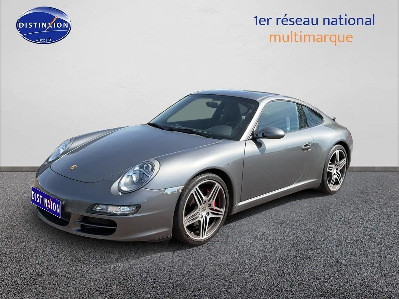 Porsche 911 (997) Carrera S gris vue 3/4 avant droit, avec jantes alu et phares bi-xénon visibles.