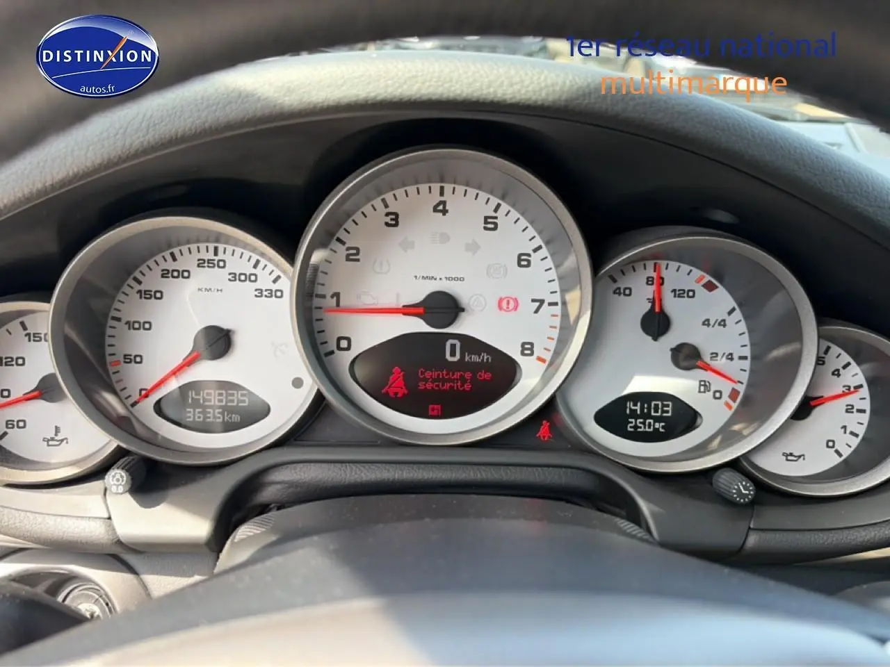 Vue rapprochée du tableau de bord de la Porsche 911 (997) Carrera S, avec compteurs blancs et affichage digital.