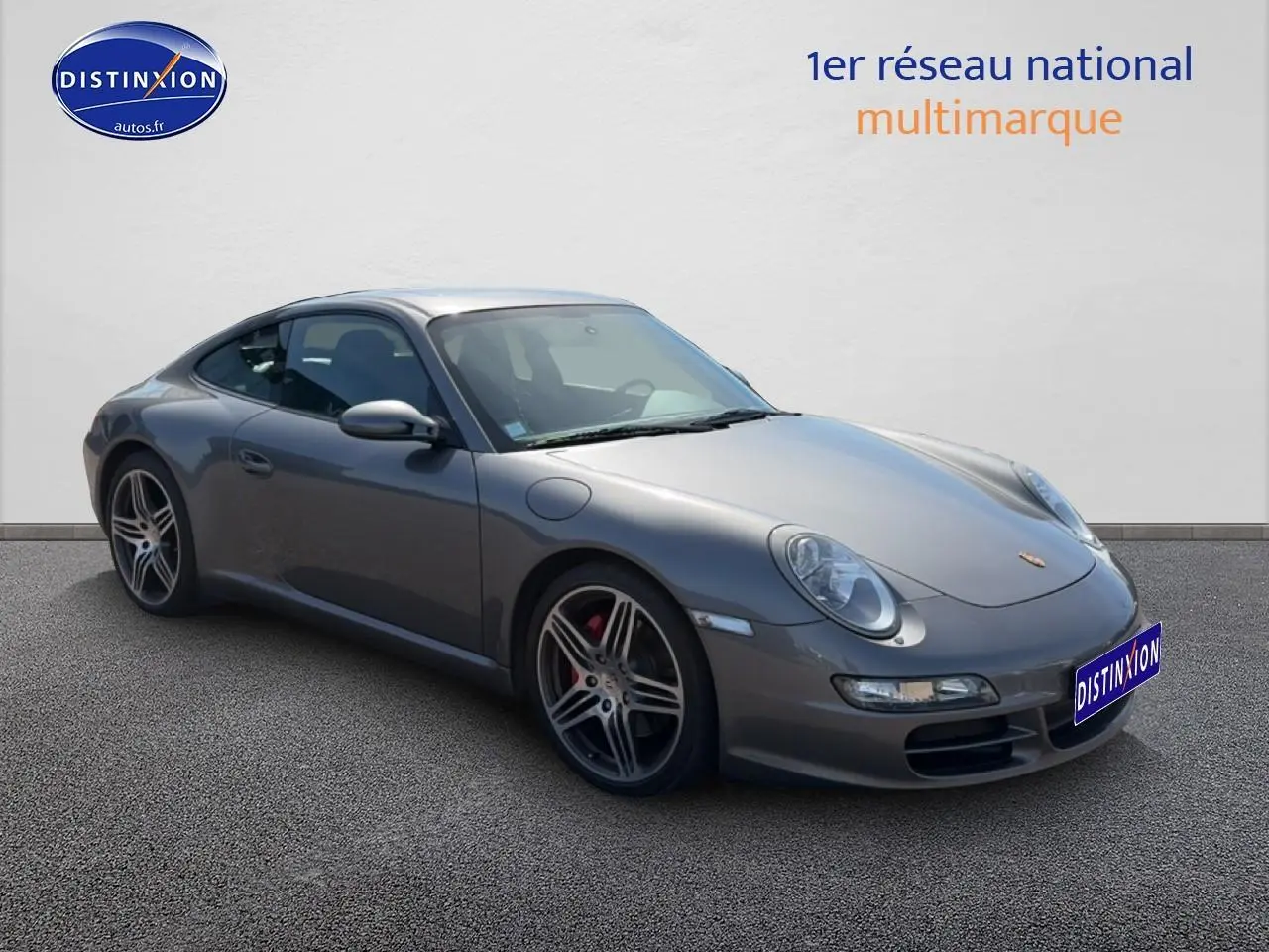Porsche 911 (997) Carrera S gris vue 3/4 avant droit, jantes alu et phares bi-xénon visibles.