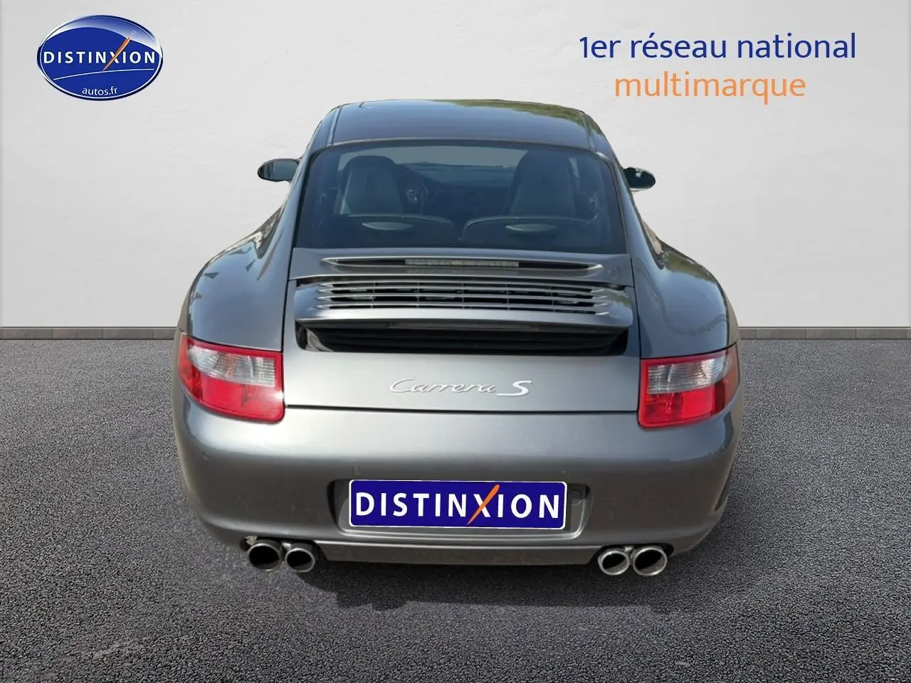 Vue arrière d'une Porsche 911 (997) Carrera S gris métallisé avec double sortie d'échappement et aileron intégré.