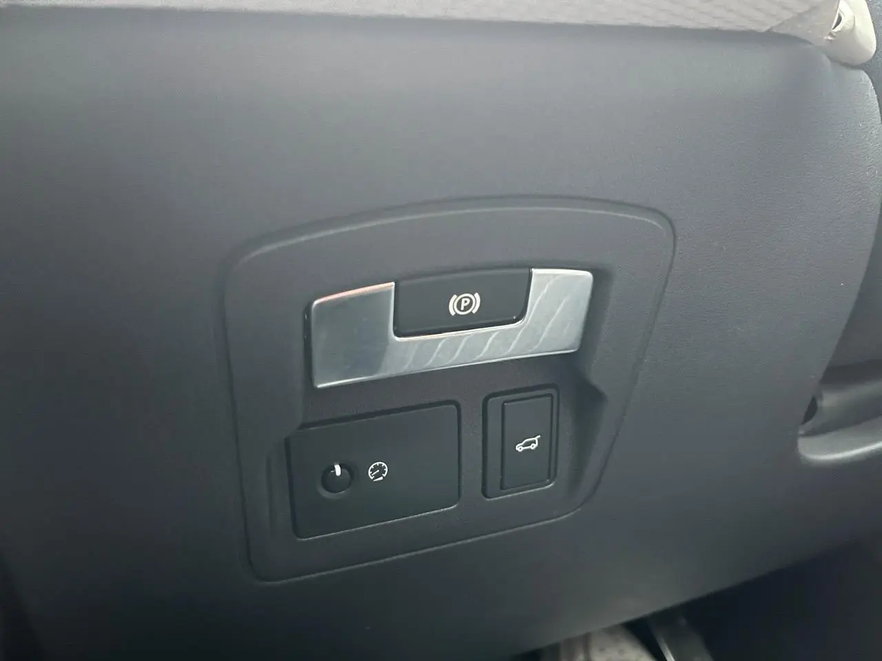 Détail du tableau de bord noir avec commandes de frein à main électrique et ouverture du hayon sur Range Rover Velar gris Ammonite.
