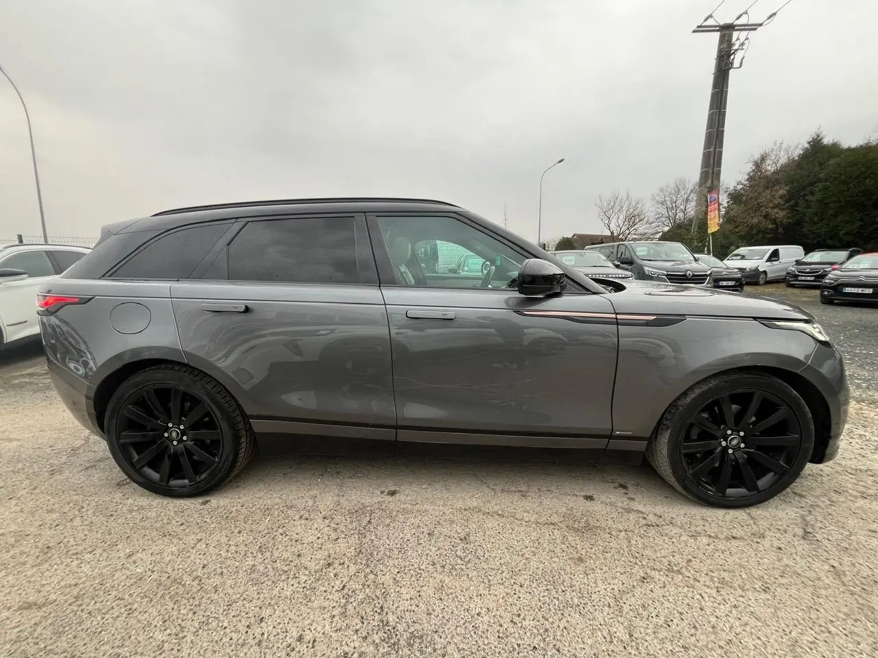 Vue latérale gauche d'un Range Rover Velar gris ammonite avec jantes noires 21 pouces et toit panoramique.