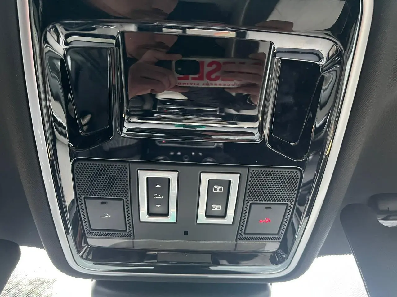 Vue en contre-plongée du panneau de commande du toit ouvrant panoramique du Range Rover Velar gris ammonite, avec boutons et éclairage rouge.