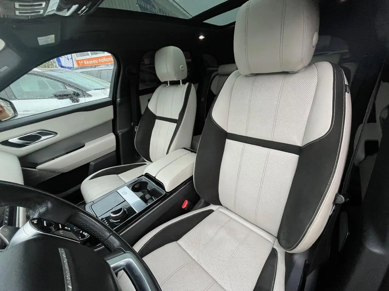 Vue intérieure du Range Rover Velar 2017 montrant les sièges avant bicolores beige et noir avec console centrale brillante.